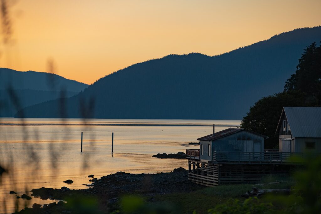 Sunset over the Southeast Alaska coastline near Wrangell with calm ocean waters, mountain scenery, and waterfront homes connected by reliable local internet service.
